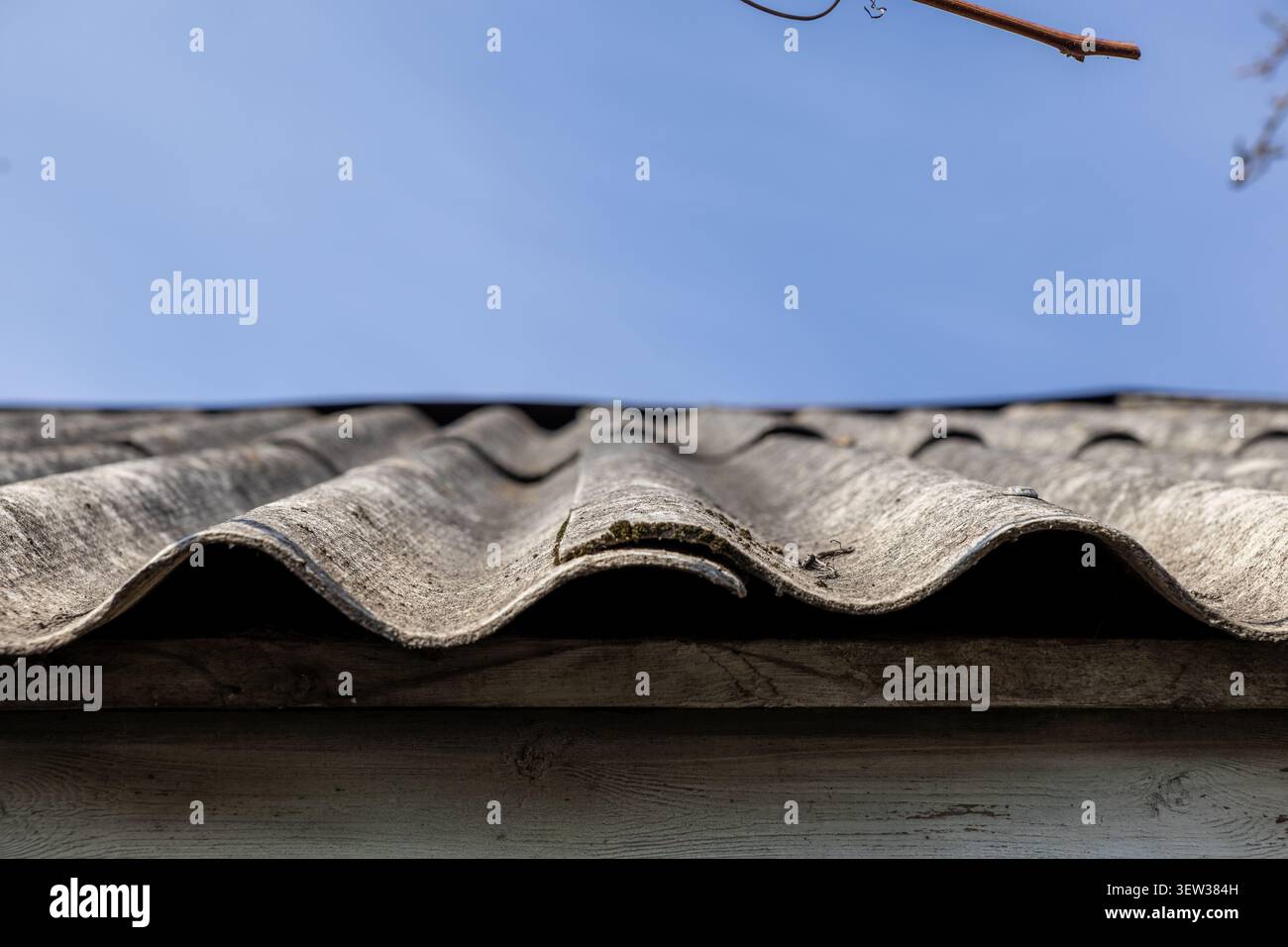 Verwitterte, wellige Dachplatten aus grauem Schiefermaterial unter einem klaren Himmel, die die robuste Oberflächenstruktur und die typischen strukturellen Details hervorheben Stockfoto