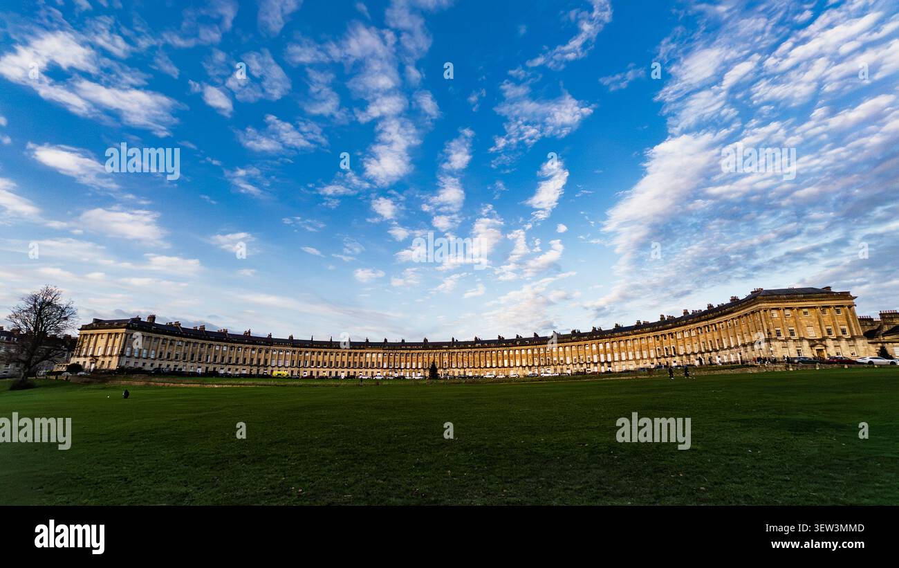 Der Royal Crescent in Bath, über einen offenen grünen Raum unter einem blauen Himmel und Wolken gesehen. - Smartphone-aufgenommenes Stockfoto