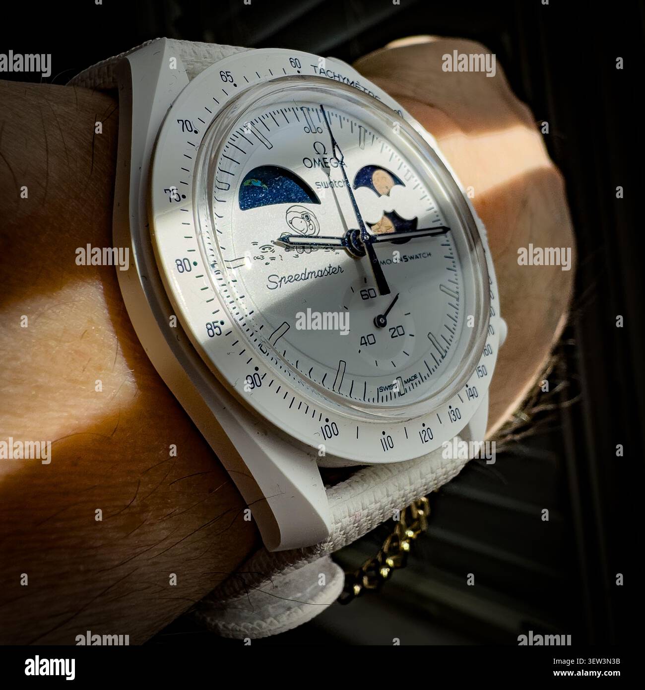 Nahaufnahme eines weißen Omega Swatch MoonSwatch Speedmaster am Handgelenk - Smartphone-aufgenommenes Stockfoto