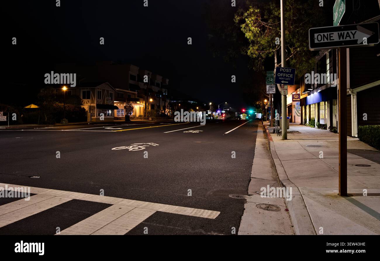 Ruhige Newport Beach Street mit Einbahnschild, Fahrradmarkierungen und Geschäften bei Nacht. Stockfoto