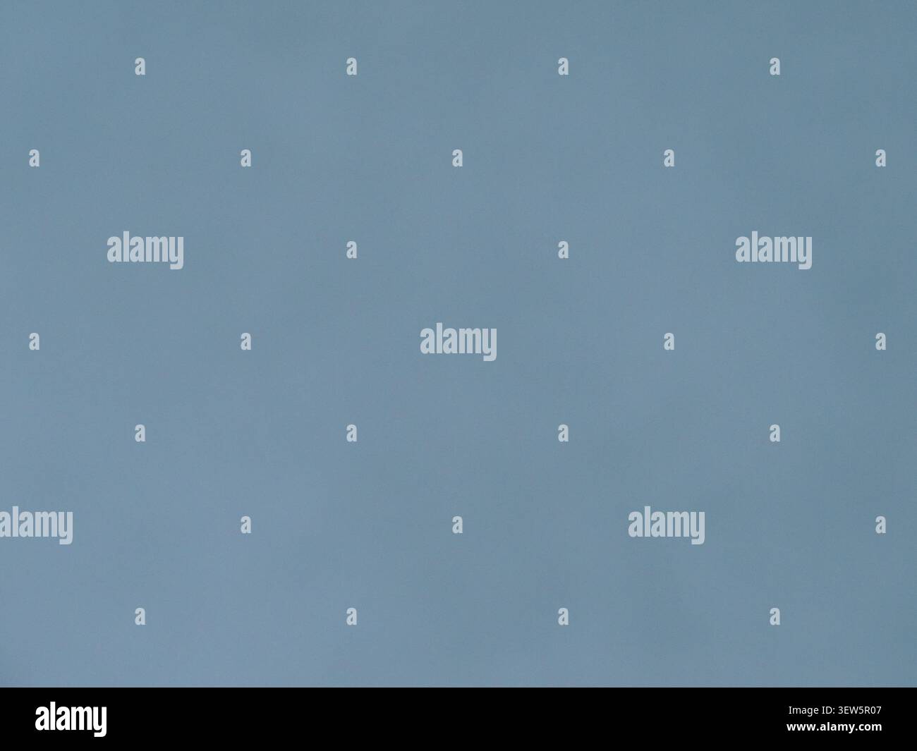 Ein minimalistischer, matter Hintergrund in gedämpftem Graublau. Die gleichmäßige, glatte Textur ohne sichtbare Nähte oder Defekte Stockfoto
