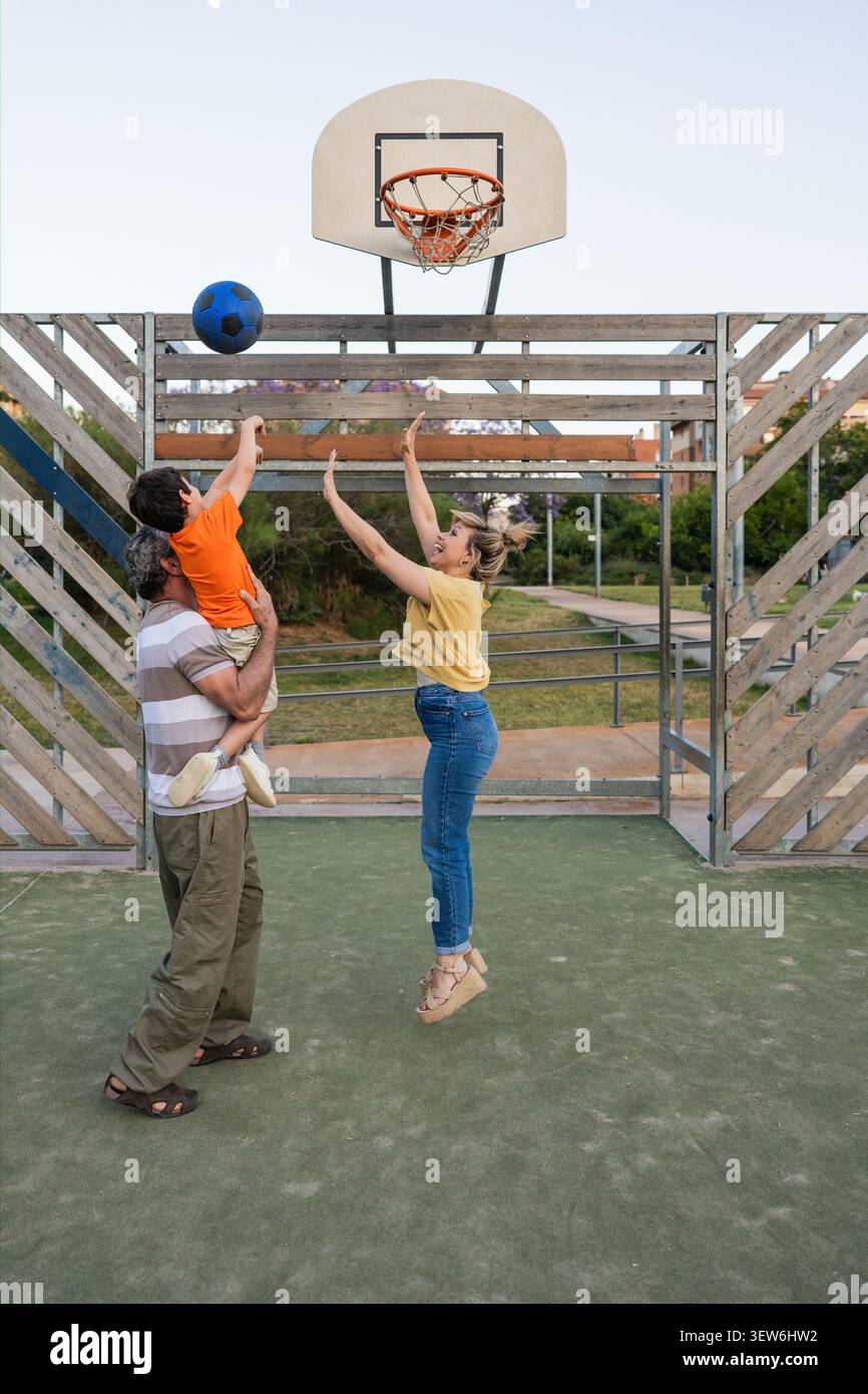 Drei Generationen spielen gemeinsam Basketball im Freien Stockfoto