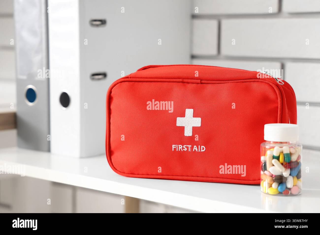Rotes erste-Hilfe-Set mit Pillenflasche auf weißem Regal Stockfoto