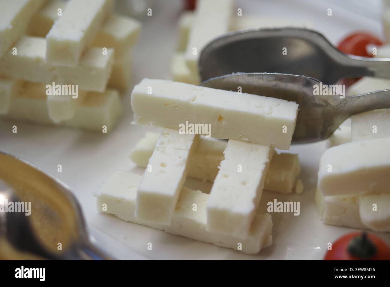 Käse wird auf einer weißen Platte mit kleinen Tomaten serviert Stockfoto