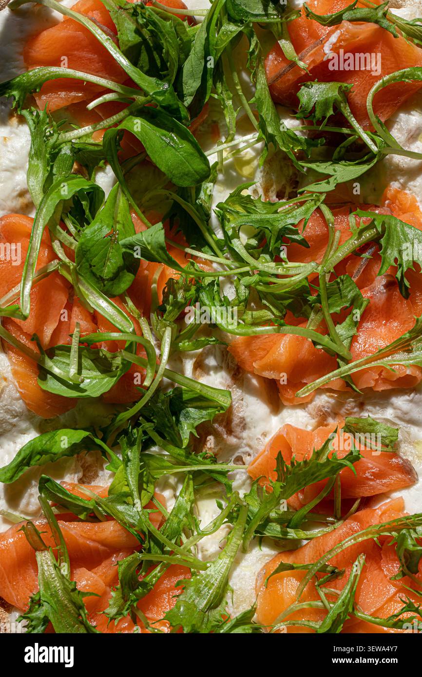 Gourmet-Lachs-Pizza mit frischer Rucola aus nächster Nähe Stockfoto