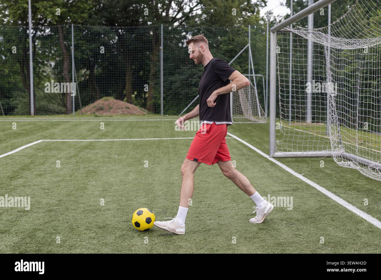 Ein männlicher Fußballspieler übt seine Dribbling- und Schießkünste während eines Trainings auf einem Außenfeld aus. Stockfoto