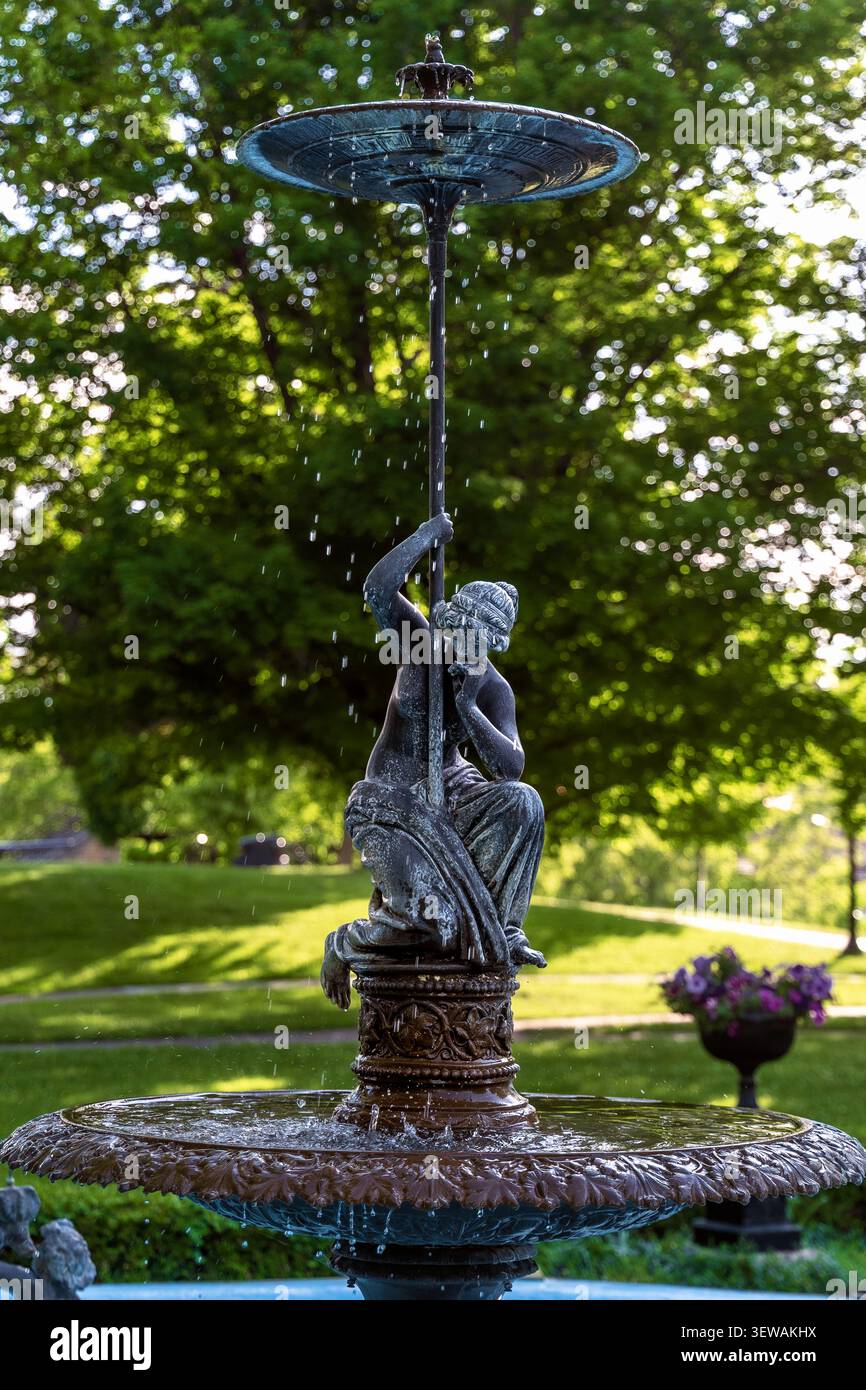 Galena, Illinois, USA - 29. Mai 2026: Dekorativer, gestufter Brunnen mit einer sitzenden klassischen Figurenskulptur in Grant Park, Galena, Illinois, mit W Stockfoto
