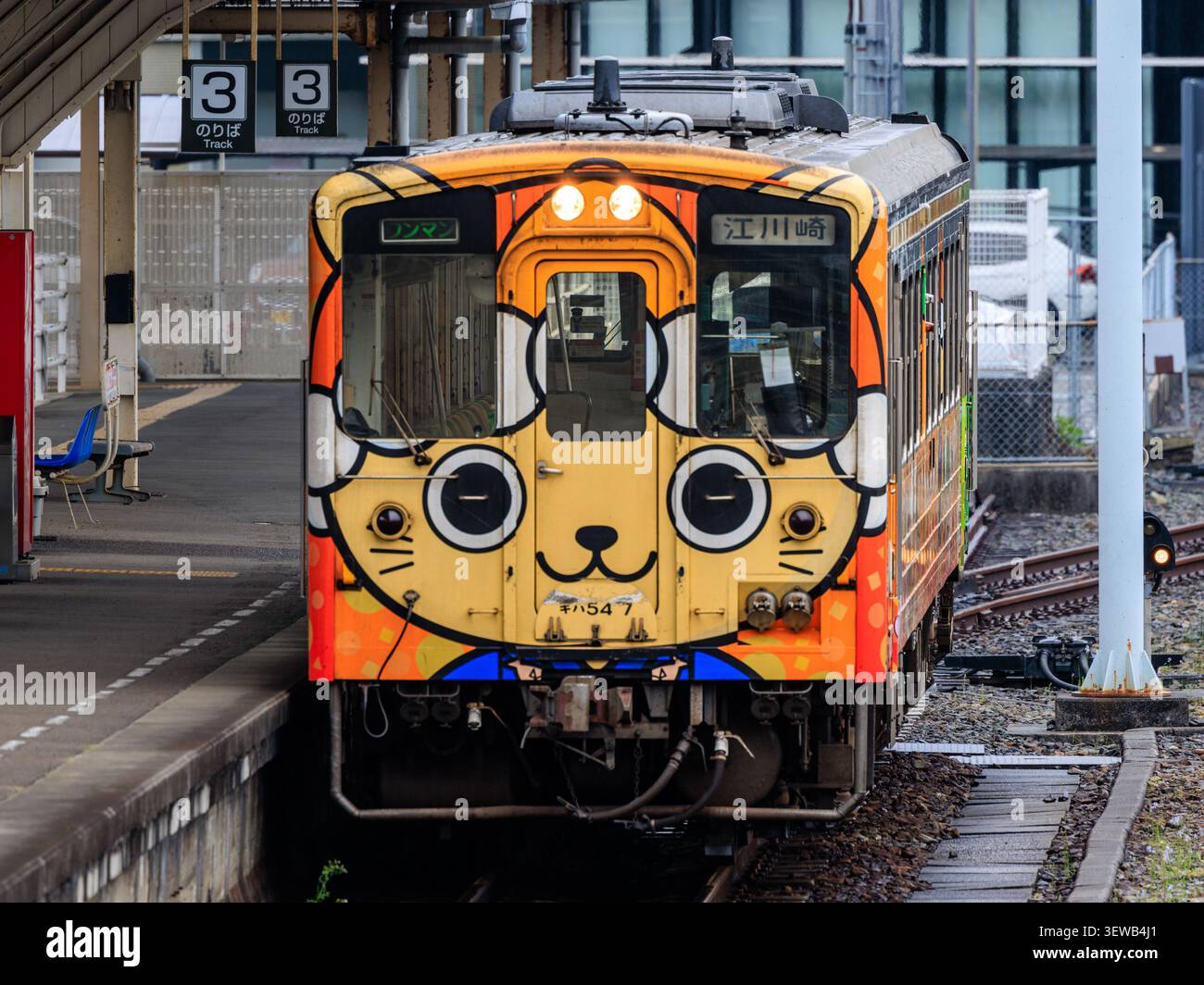 Ein farbenfroher Pendelzug, der mit einem großen Cartoon-Katzen-Gesicht bemalt ist, wartet auf dem Bahnsteig des Bahnhofs Uwajima in Japan Stockfoto