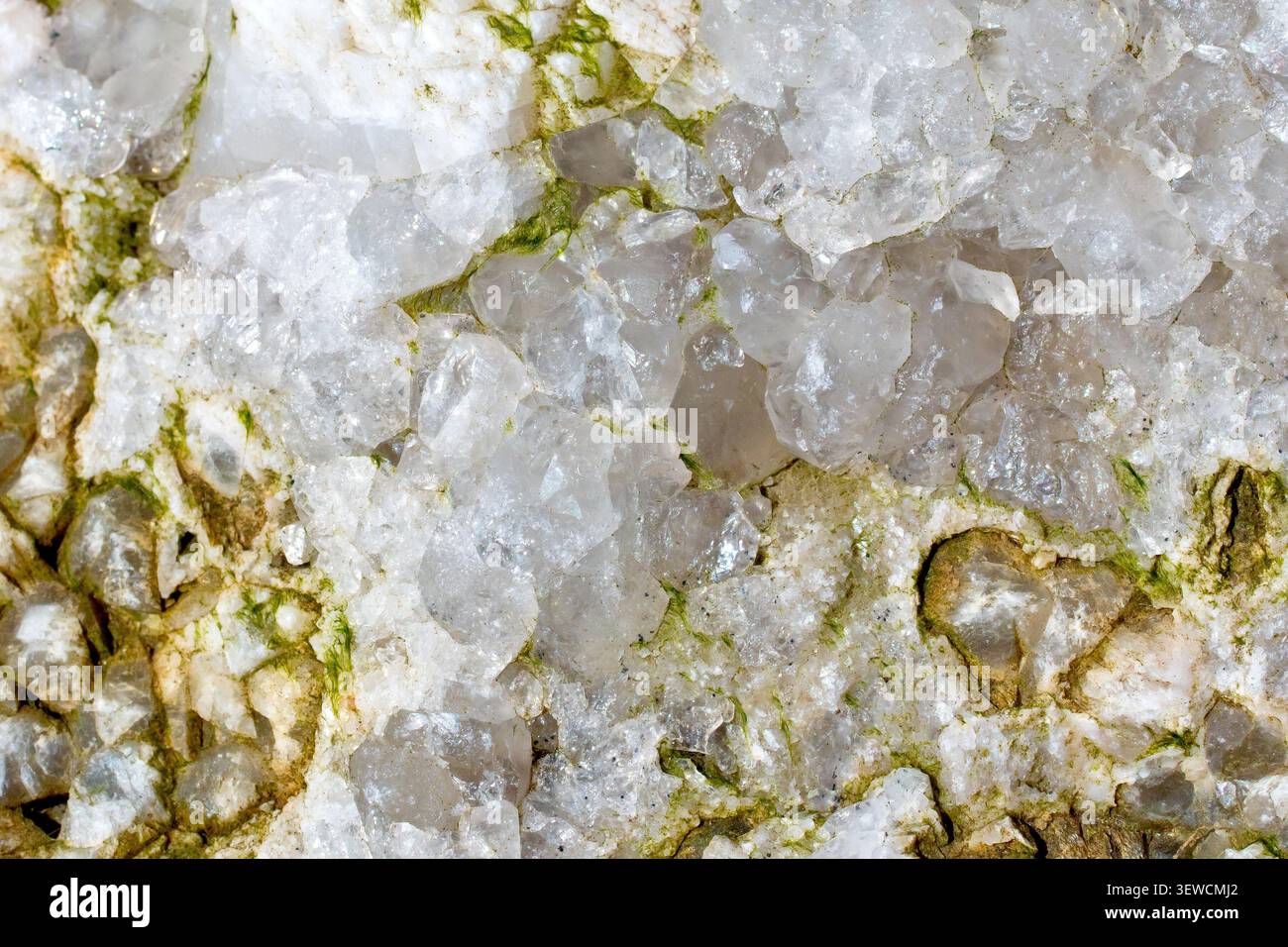 Nahaufnahme mit Kristallen des Mineralquarzes (Kieselsäure), eingebettet in eine Spalte auf einem Basaltblock. Stockfoto
