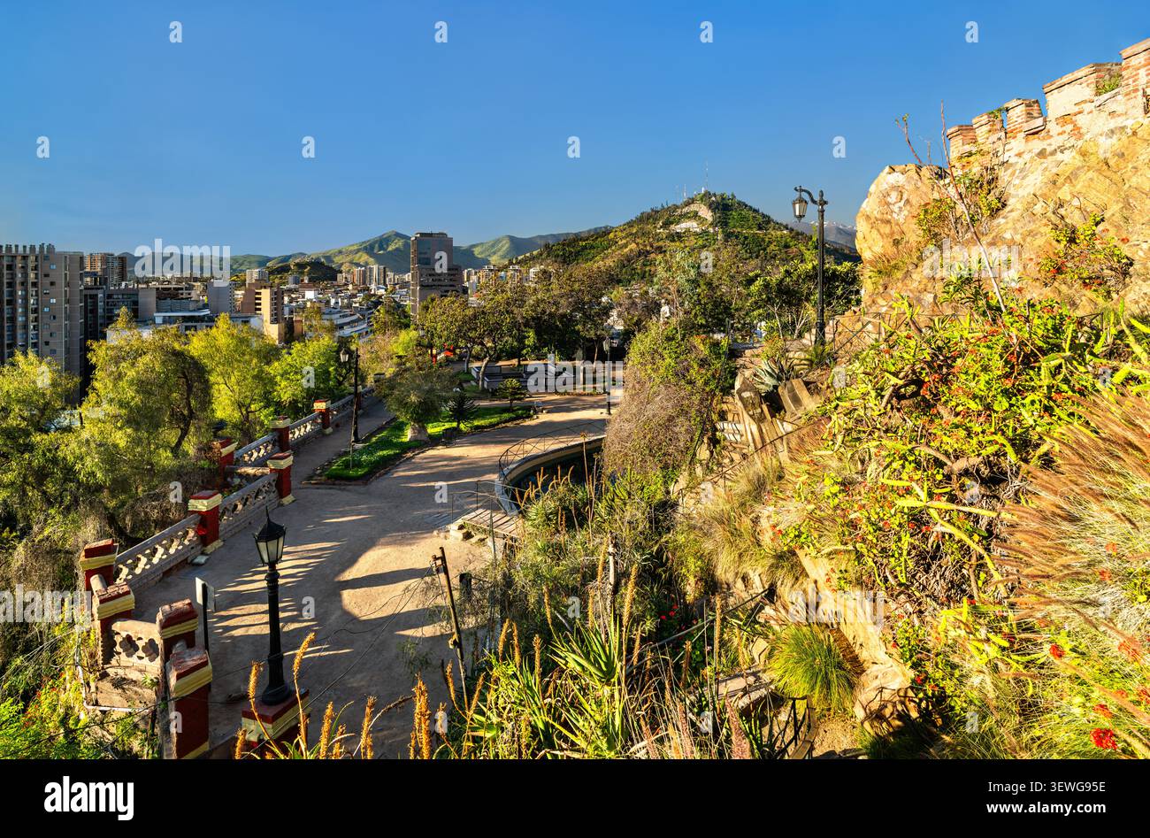 Ein wunderschönes Panorama von Santiago, Chile, vom historischen Santa Lucia Hügel aus gesehen, mit üppigen Gärten, Steinpfaden und der Skyline der Stadt unter einem klaren blauen Himmel. Stockfoto