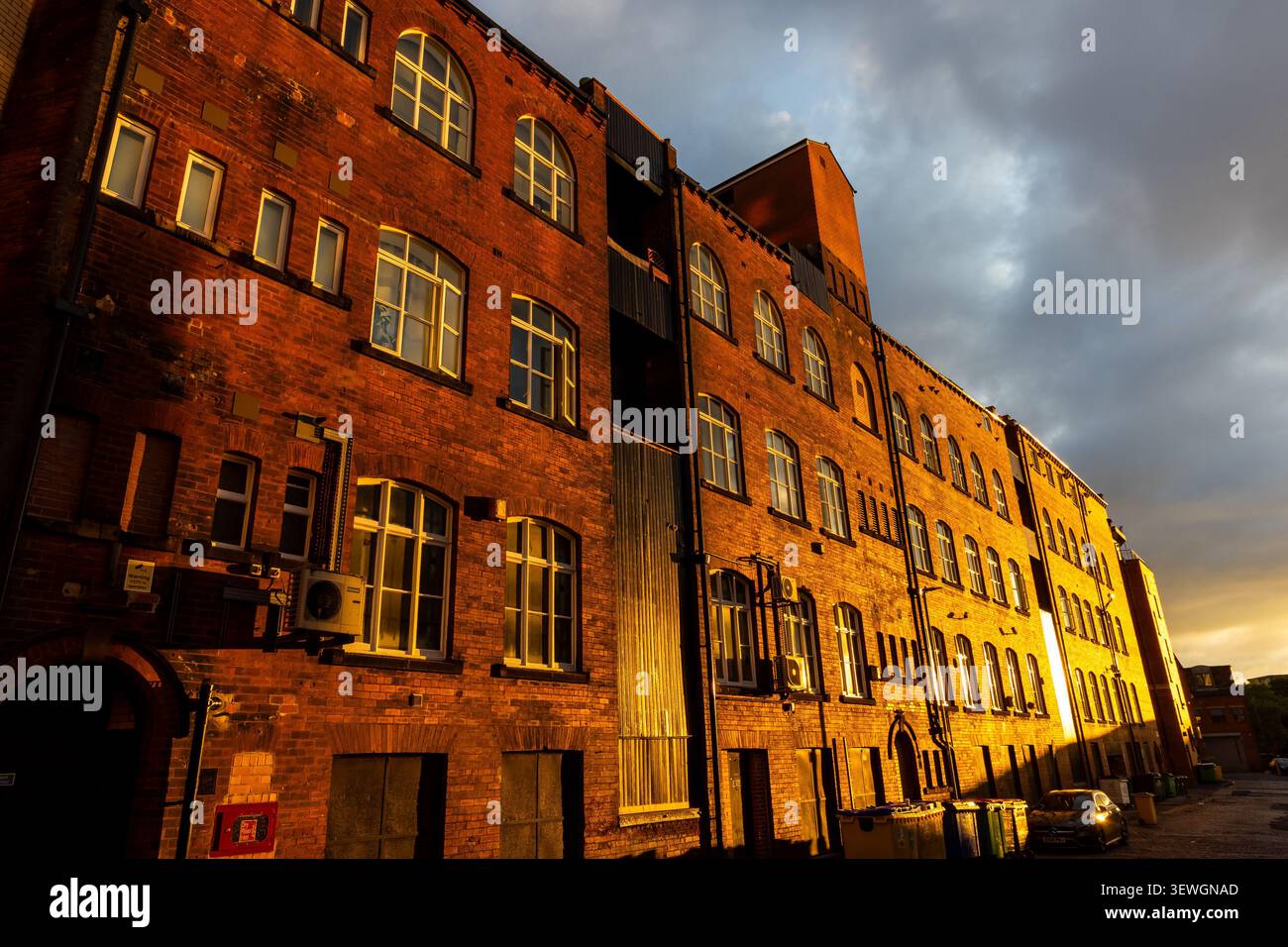 Das alte Backsteinwerk leuchtet im Morgenlicht Golden vor dem bewölkten Leeds-Himmel Stockfoto