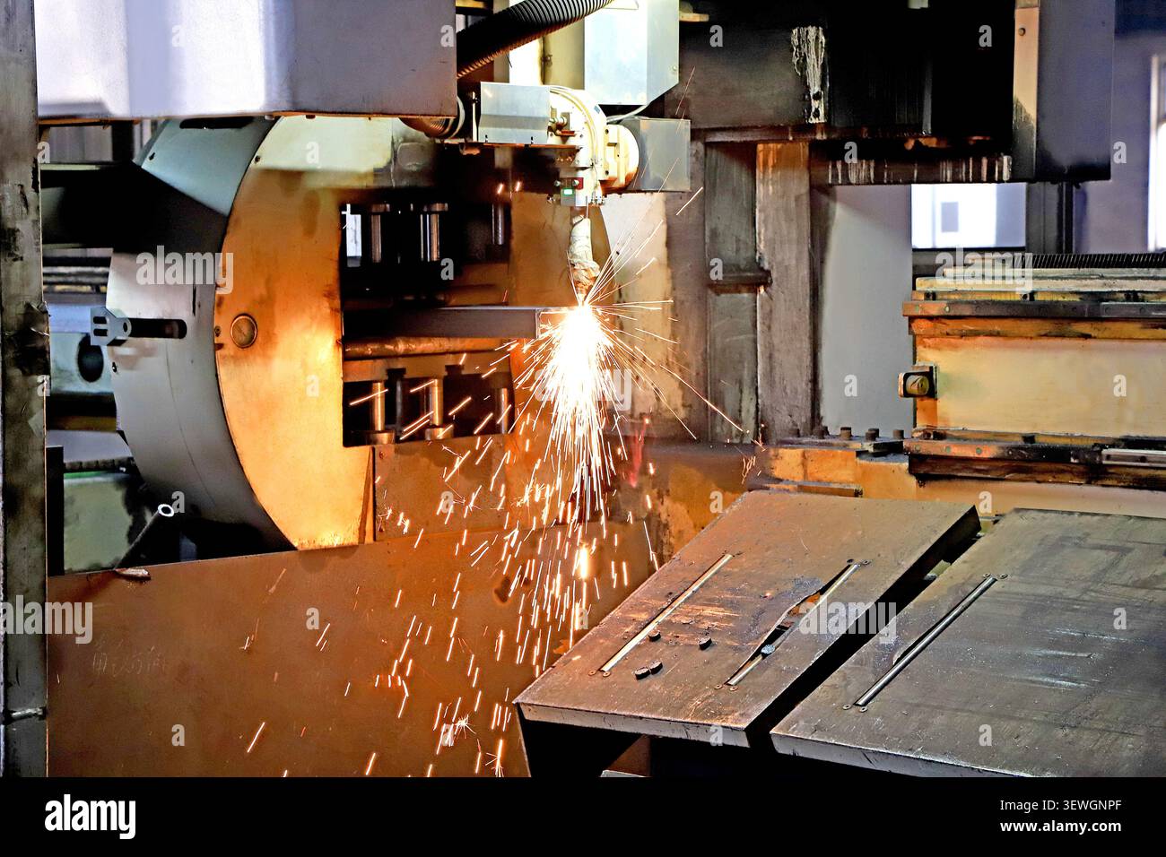 Eine hochenergetische, hochauflösende Nahaufnahme eines CNC-Bearbeitungsprozesses in einer Fabrikwerkstatt, bei der ein Schneidwerkzeug einen dramatischen Aufbruch heller, heller, ora erzeugt Stockfoto