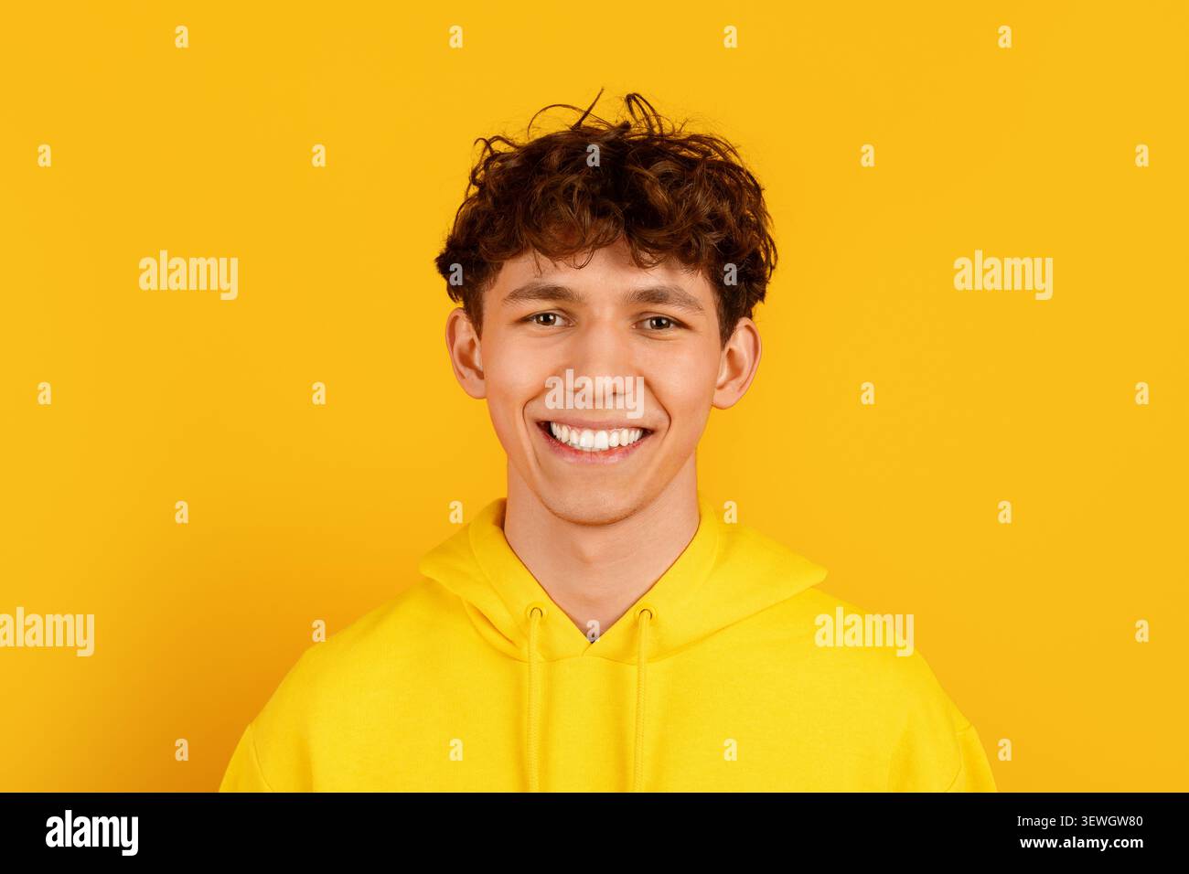 Nahaufnahme Porträt eines lächelnden jungen Mannes in gelbem Hoodie auf gelbem Hintergrund Stockfoto