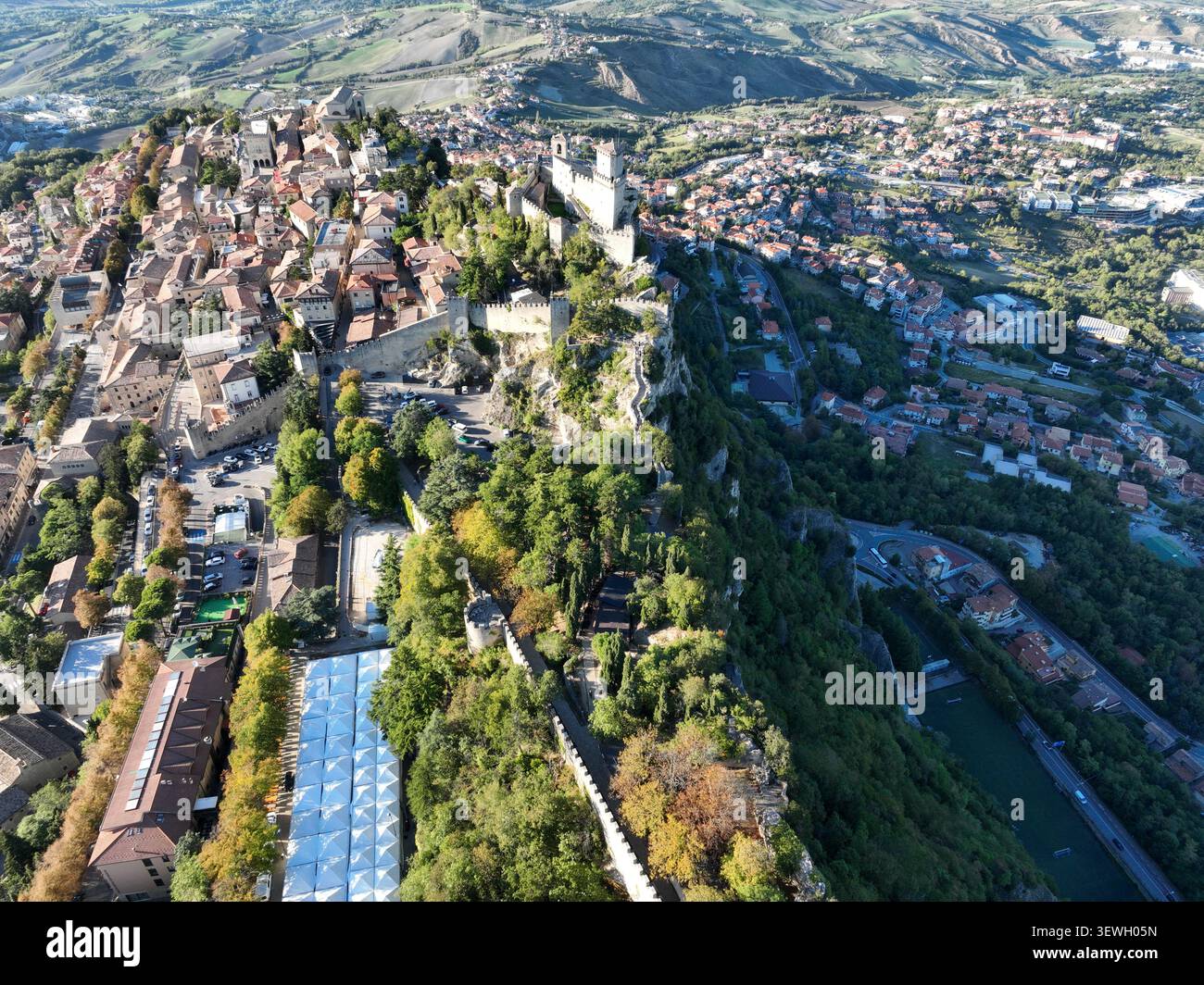 Blick aus der Vogelperspektive auf den felsigen Klippen des Mount Titano, mit Blick auf die historische Altstadt mit Steinbauten und Terrakotta-Dächern in CIT Stockfoto