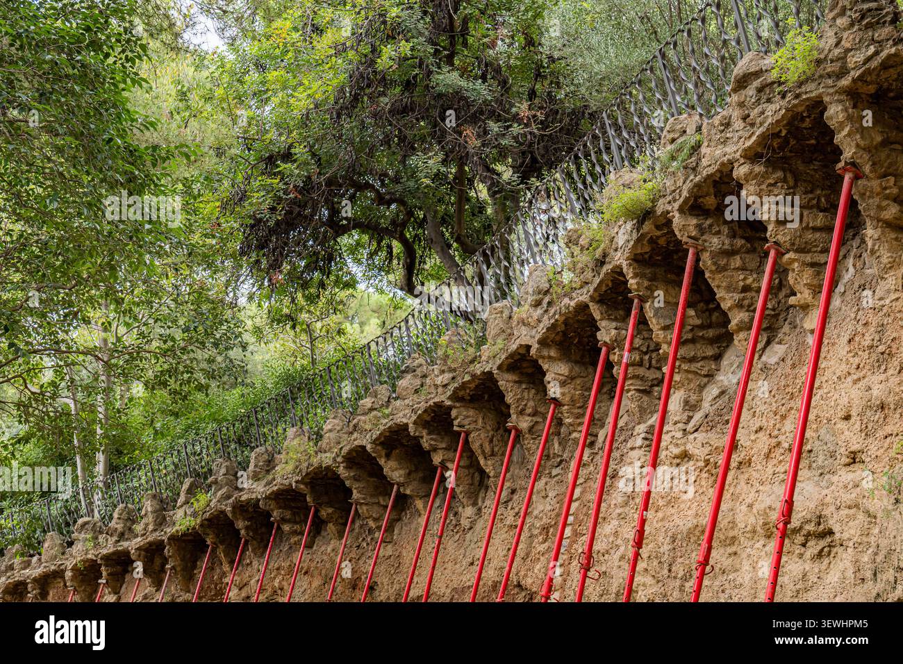 Park Güell Steinmauer mit roten temporären Stützen in Barcelona Stockfoto