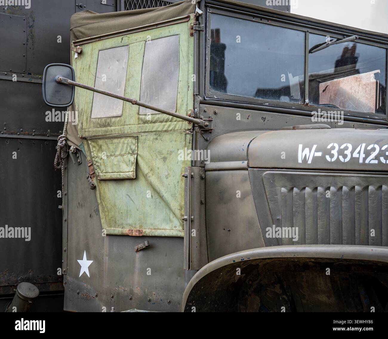 Ein klassischer GMC CCKW-Militärfahrzeug mit einem Faltverdeck mit Türen und Fenstern aus olivfarbenem Canvas. Es verfügt über ein weißes Sternenemblem und eine Registrierung. Stockfoto
