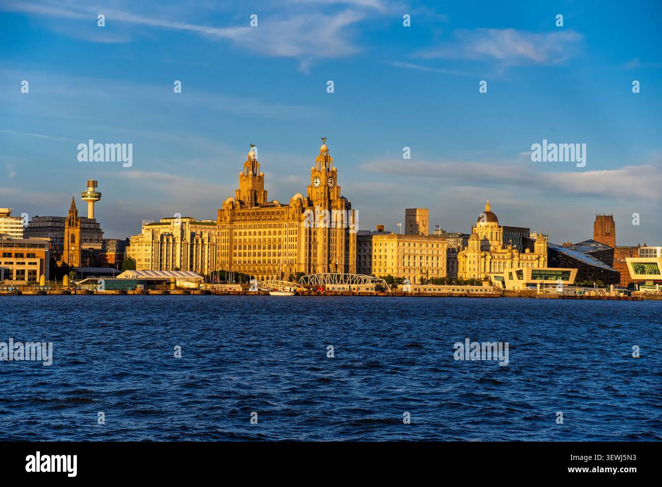 Wenn die Abendsonne untergeht, umhüllt ein warmes goldenes Leuchten das Royal Liver Building und die malerische Uferpromenade von Liverpool und reflektiert die ruhige Landschaft Stockfoto