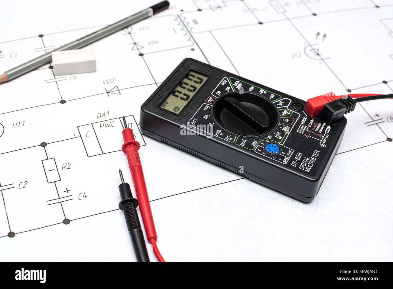 Schwarzes Digitalmultimeter mit Prüfspitzen auf elektrischer Zeichnung Stockfoto