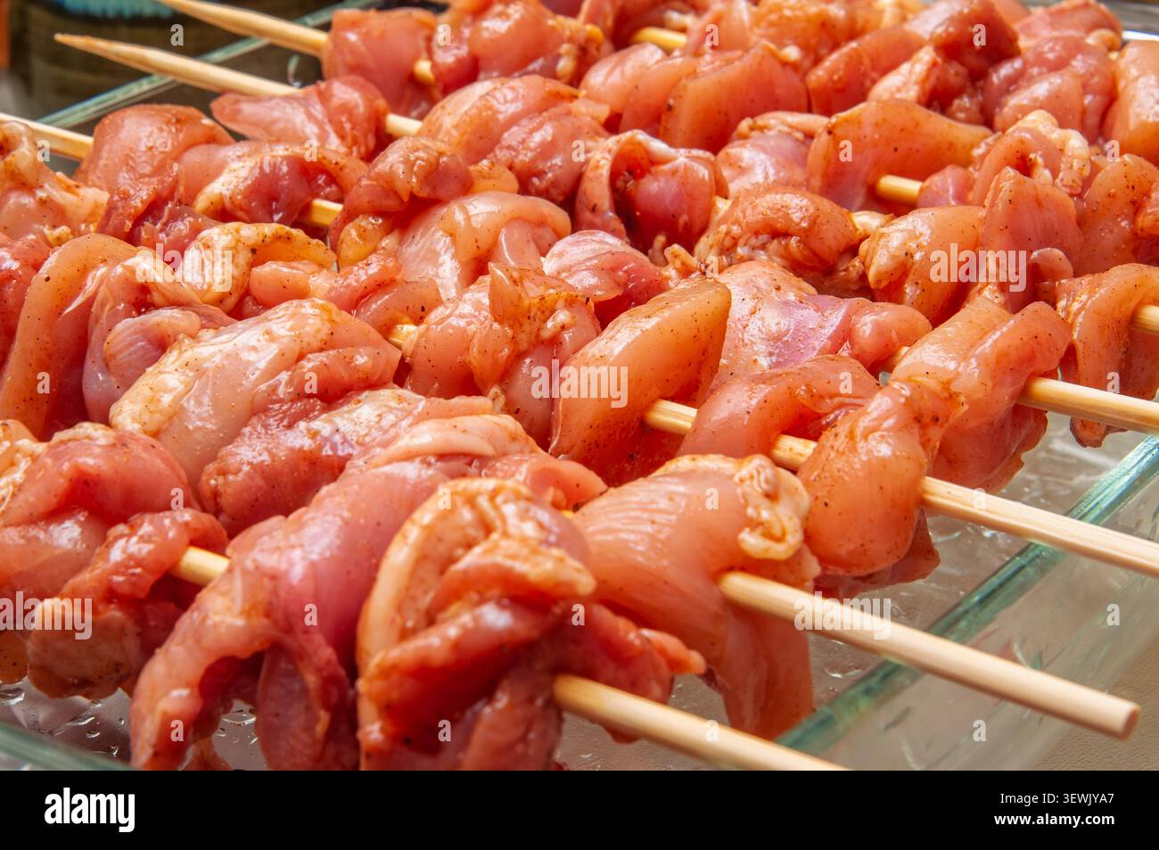Rohe gewürzte Hähnchenstücke auf Holzspieße aufgesteckt, bereit zum Kochen Stockfoto