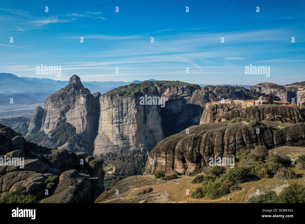 Eine Weitwinkelaufnahme der Region Meteora in Griechenland mit dramatischen Sandsteinsäulen und einem Kloster mit roten Ziegeldächern Stockfoto