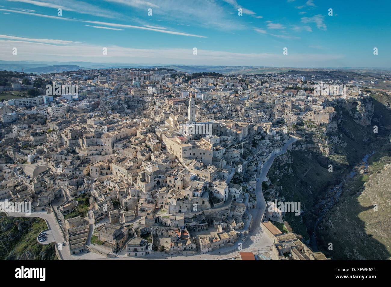 Ein weitläufiger Blick aus der Luft fängt die alten Höhlenhäuser von Sassi di Matera ein, die zum UNESCO-Weltkulturerbe gehören und einen Hügel hinunterragen. Die Gravina Stockfoto