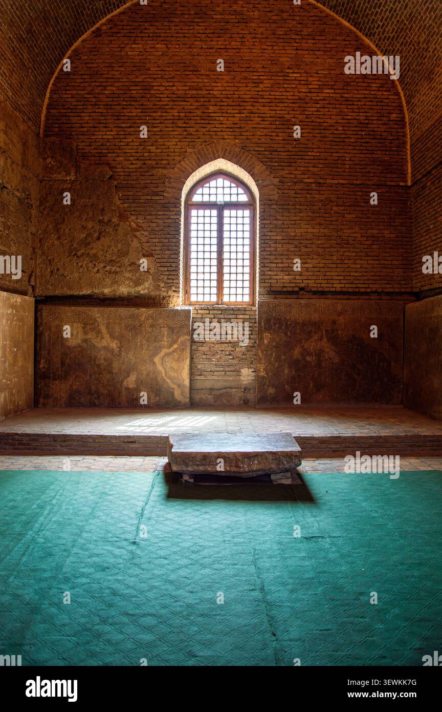 Vertikale symmetrische Aufnahme einer Innenhalle in der Blauen Moschee. Ein großes bogenförmiges Fenster mit Holzgittergitter beleuchtet den Raum Stockfoto