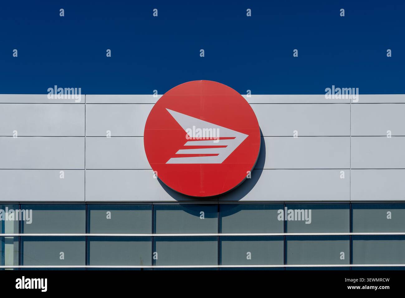 Rotes kreisförmiges Logo der Canada Post im Großverkauf auf der Außenseite einer Niederlassung der Canada Post in Toronto. Stockfoto