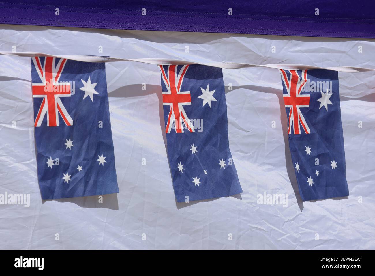 Als festliche Dekoration vor weißem Stoffmotiv für eine nationale Feier oder öffentliche Veranstaltung hängt die australische Flagge Stockfoto
