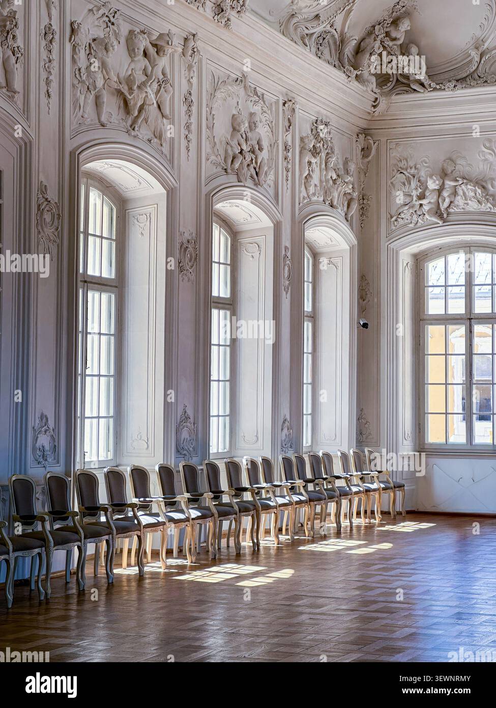 Rundale, Lettland - 26. Juni 2026: Heller Rokoko-Palastsaal mit kunstvollen Stuckreliefs, eleganten Stühlen, hohen Bogenfenstern und poliertem Parkettboden Stockfoto