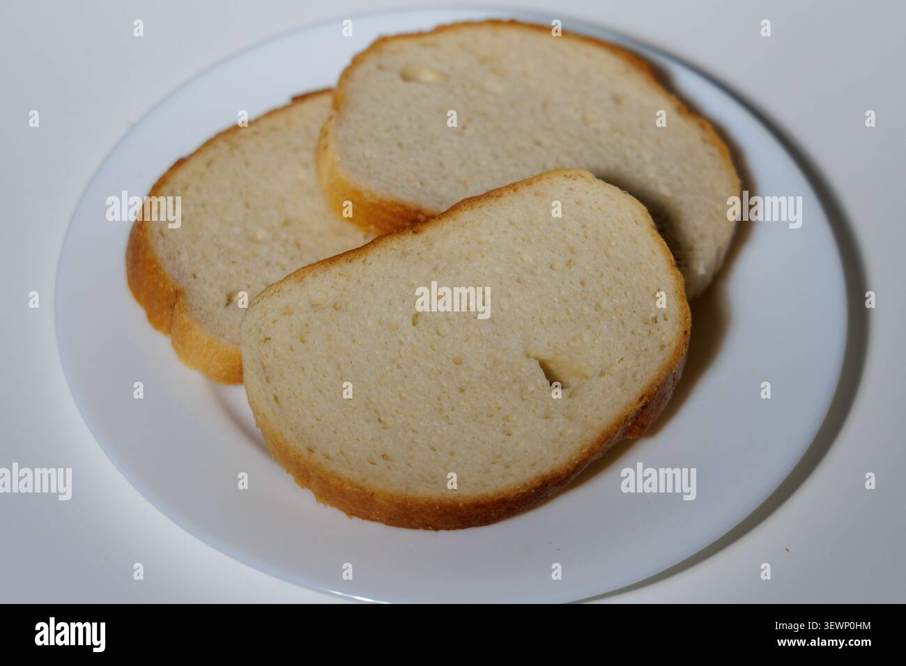 Drei Scheiben Weißbrot mit goldener Kruste. Das Brot ist weich, luftig und voller winziger Bläschen. Stockfoto