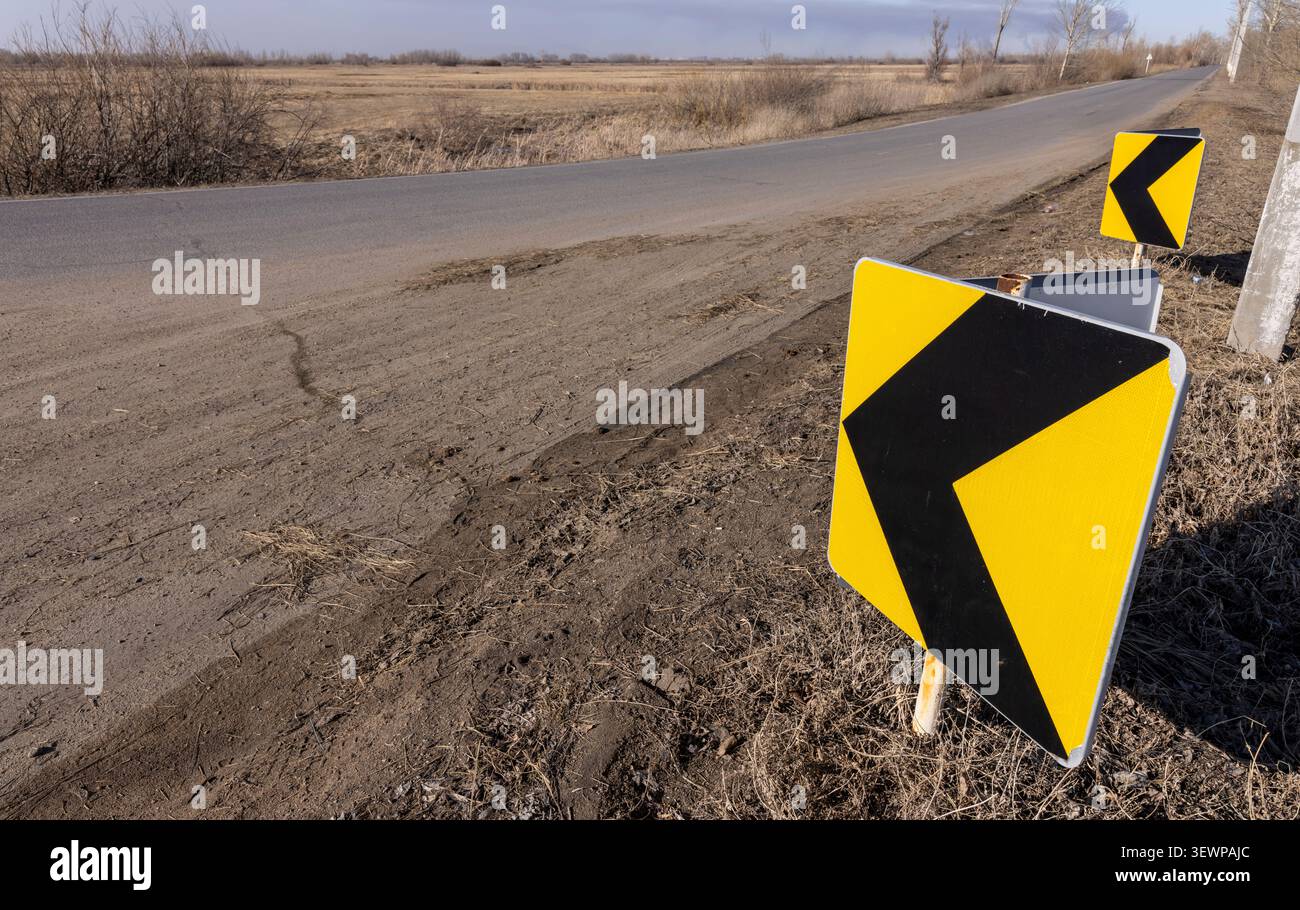Verkehrsschild am Straßenrand, schwarzer Pfeil auf gelbem Hintergrund, Umleitungsschild Stockfoto