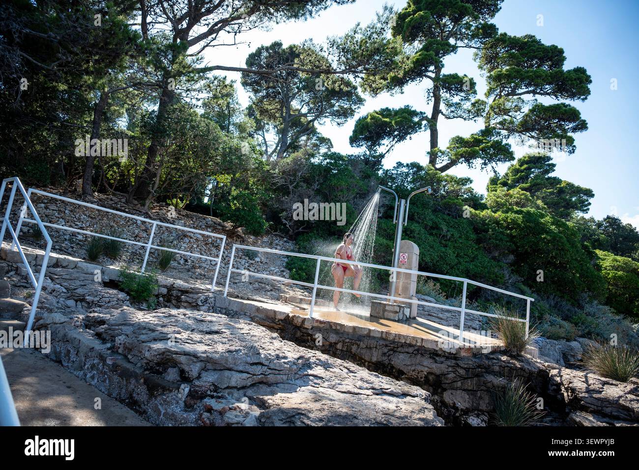 Person, die an einem Strand auf der Insel Lokrum duscht, vor der Küste von Dubrovnik, Kroatien. Stockfoto