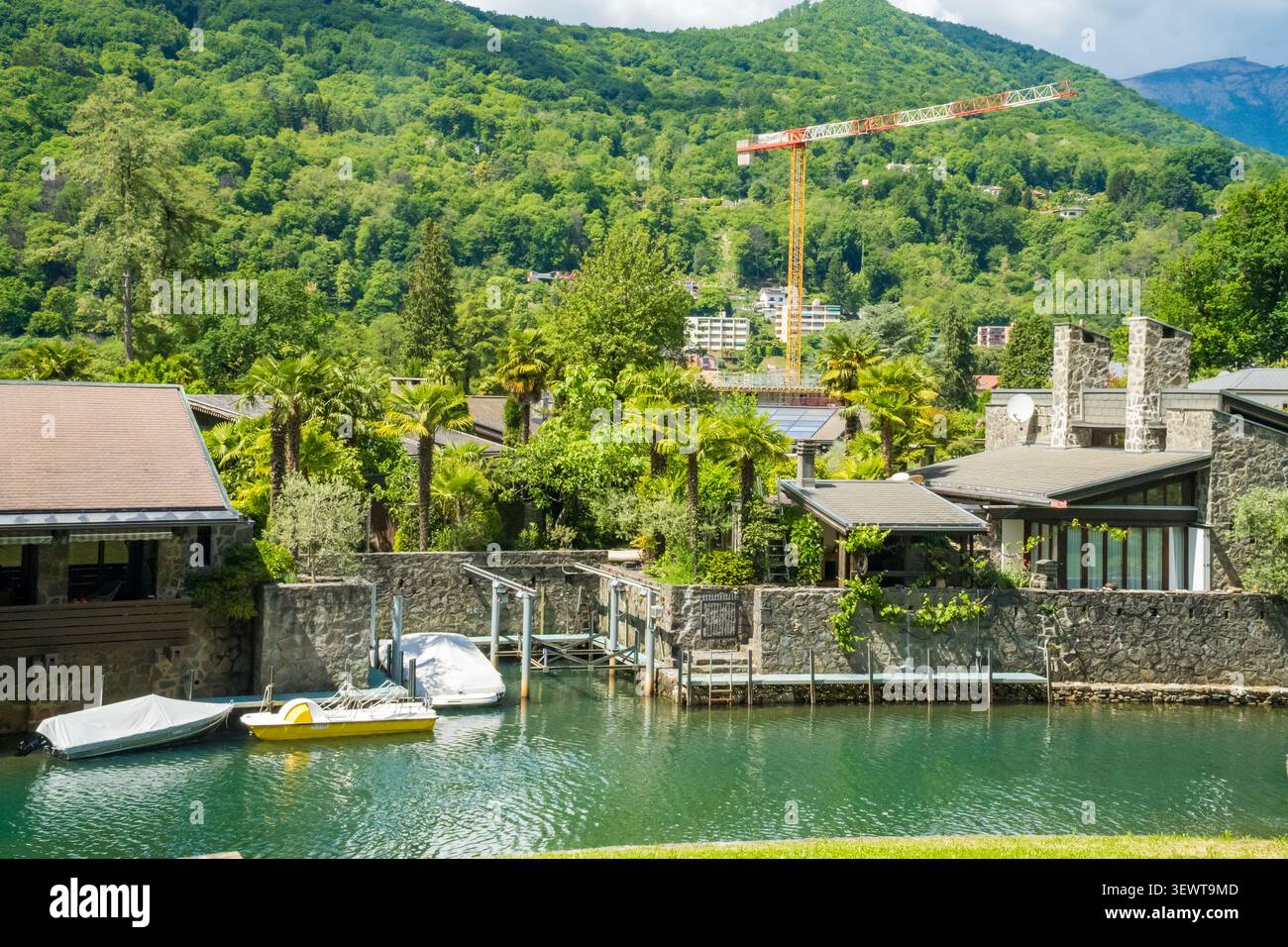 Steinhäuser Kanalbote Baukran grüne Hügel Schweiz Stockfoto