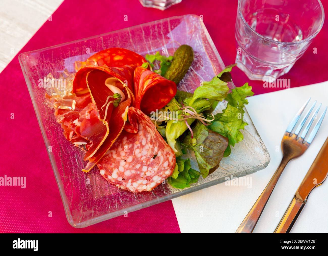 Platte mit kaltem Fleisch mit Salat und eingelegten Gurken in der Nähe. Französische Küche Stockfoto