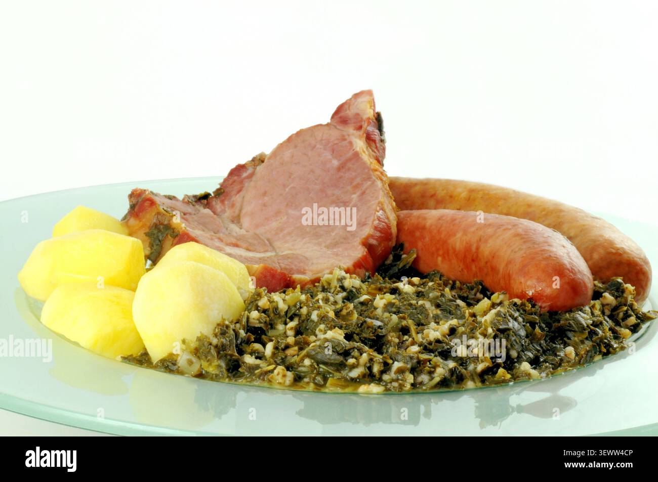 Traditionelles norddeutsches Grünkohl serviert mit Kartoffeln, Kassler und geräucherten Würstchen wie Mettwurst und Kohlpinkel. Eine herzhafte Wintermesse Stockfoto