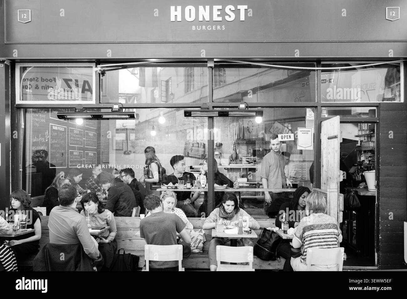 Gäste genießen Speisen und Getränke im Honest Burgers in Brixton Market, London, und treffen sich zu einem geselligen Essen in der lebhaften Nachbarschaft. Stockfoto