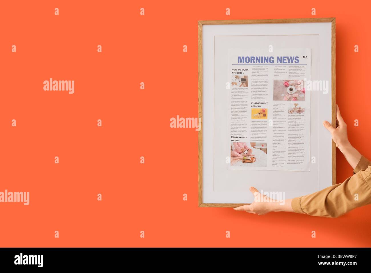 Person mit gerahmtem Morgennachrichten auf orangem Hintergrund Stockfoto