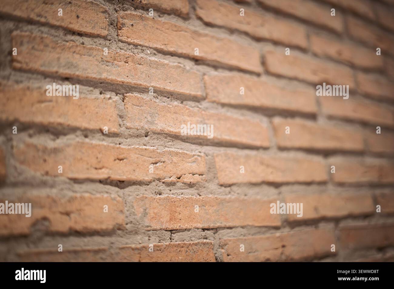 Aus nächster Nähe eine Backsteinmauer mit rauen orangen Tonblöcken, sichtbaren Mörtelfugen und flachem Fokus, die rustikale Mauerwerkstextur für eine hervorhebt Stockfoto