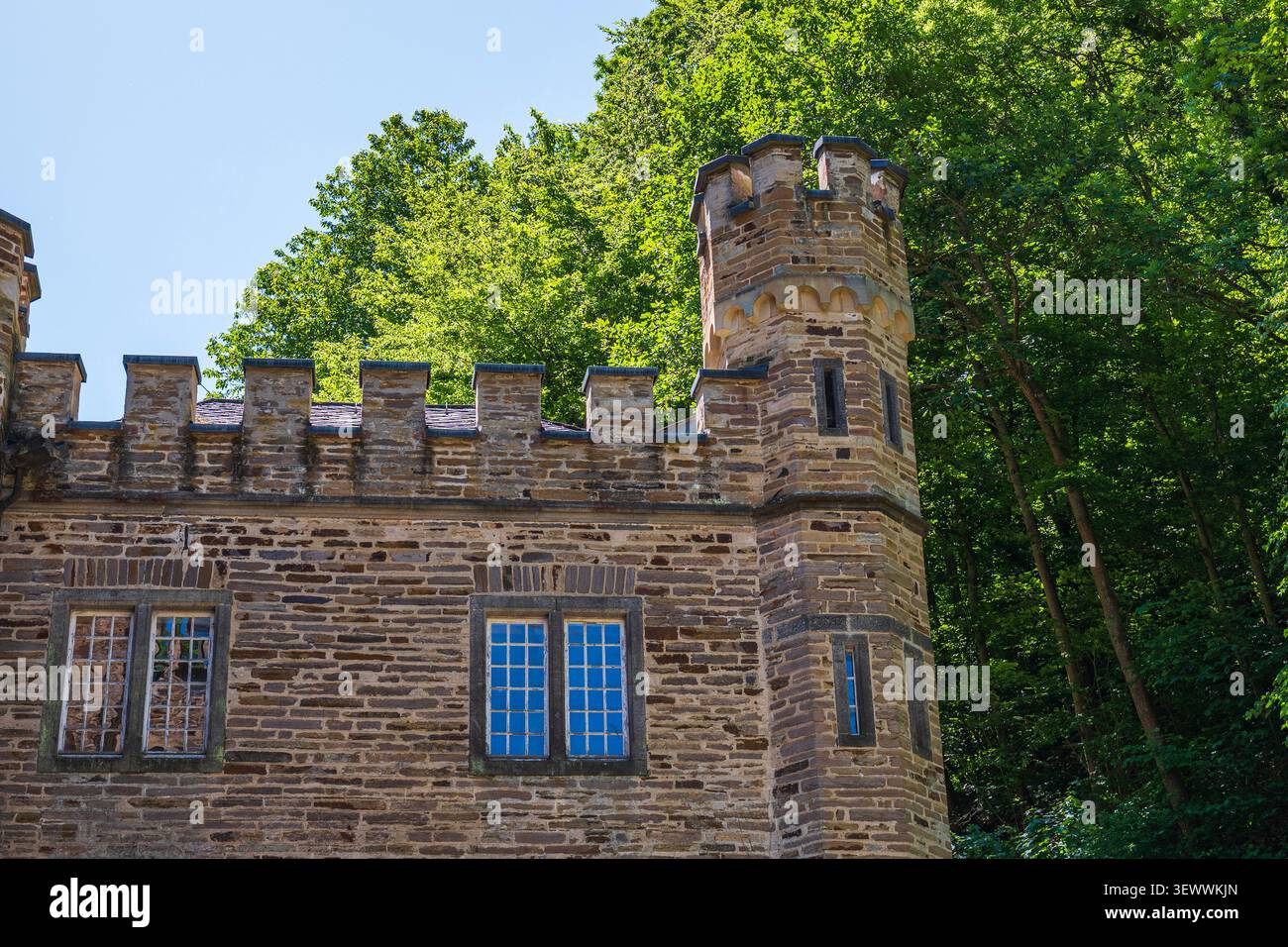 Burgsteinturm alte Festungsmauer mit Fenstern vor grünen Waldbäumen und blauem Himmel, mittelalterliche europäische Architektur Wahrzeichen, historische sie Stockfoto