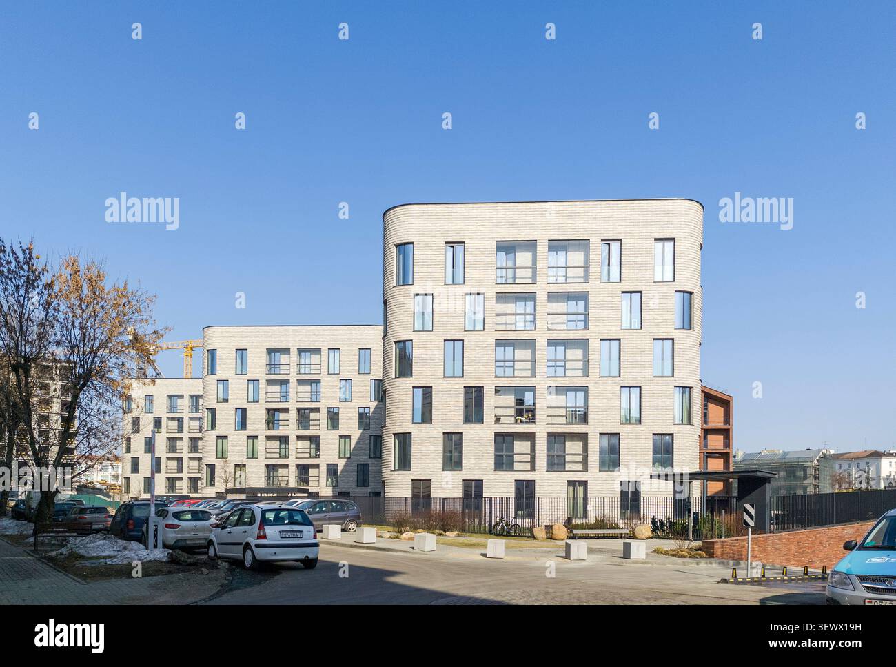 Minsk Weißrussland März 30 2026 an der Straße erheben sich luxuriöse Wohngebäude mit geparkten Autos. Der moderne Apartmentkomplex zeigt gehobene städtische Wohnumgebung Stockfoto