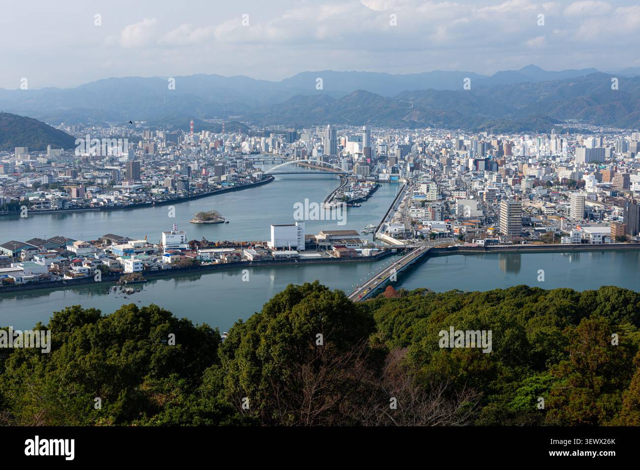 Stadtbild von Kochi mit dem Kagami-Fluss, Brücken, dichten Gebäuden und Bergen im Hintergrund, Shikoku, Japan, leicht bewölkter Tag Stockfoto