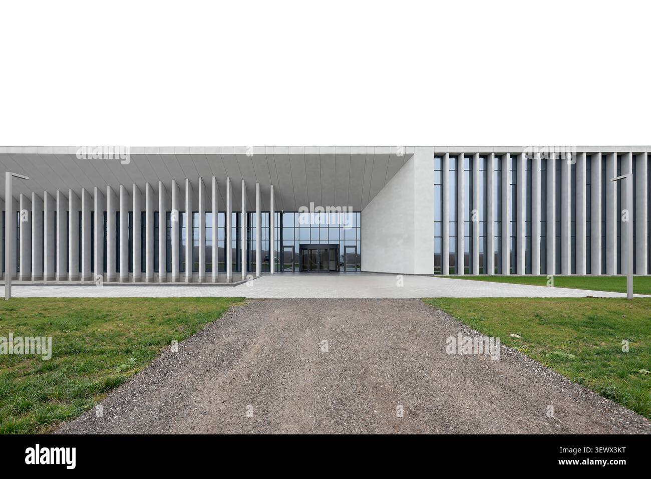 Minimalistische Betonarchitektur mit langer Kolonnade und zentralem Weg, der zur Fassade führt. Symmetrische Struktur mit sich wiederholenden vertikalen Elementen und ge Stockfoto