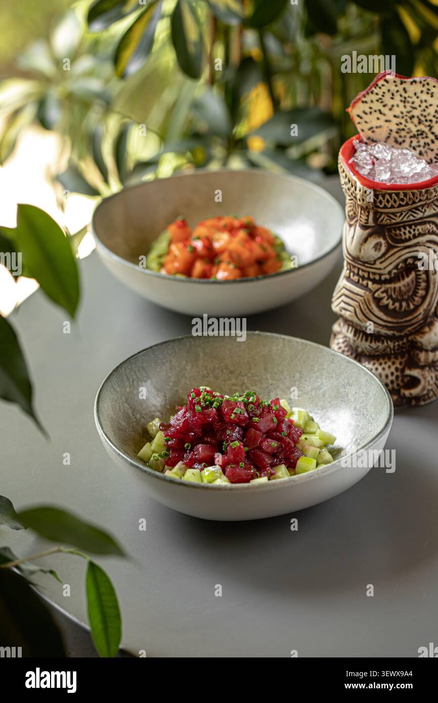 Thunfisch- und Lachs-Poke-Schüsseln mit Tiki-Cocktail Stockfoto