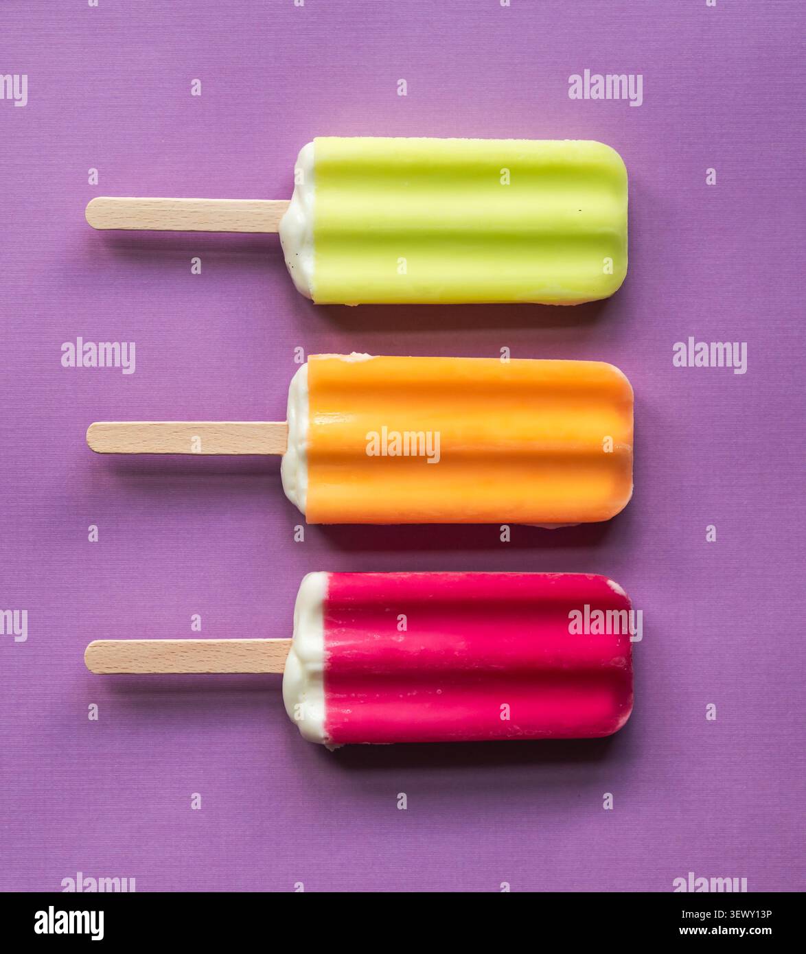 Drei bunte Eispops auf einem violetten Hintergrund Stockfoto