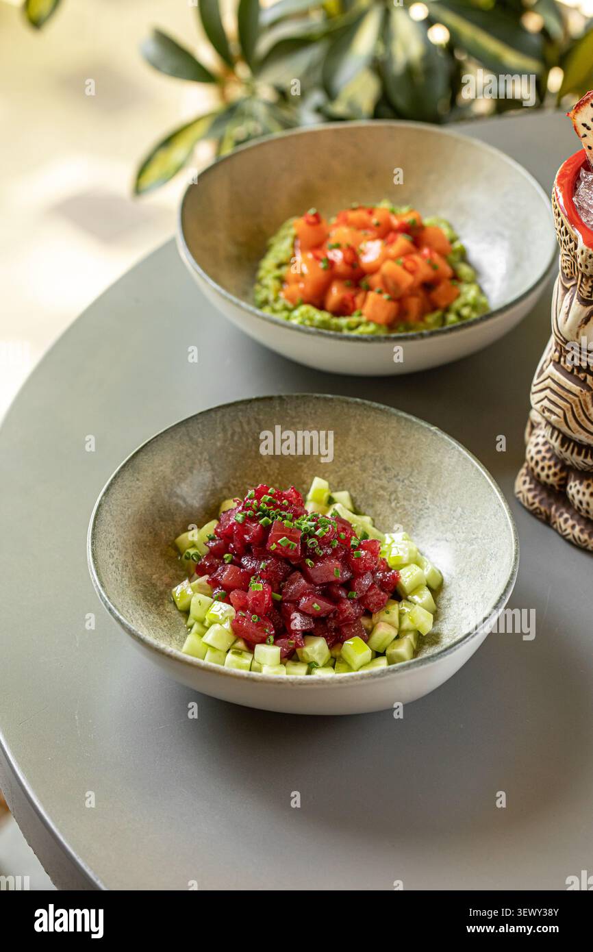 Thunfisch- und Lachs-Poke-Schüsseln mit Tiki-Cocktail Stockfoto