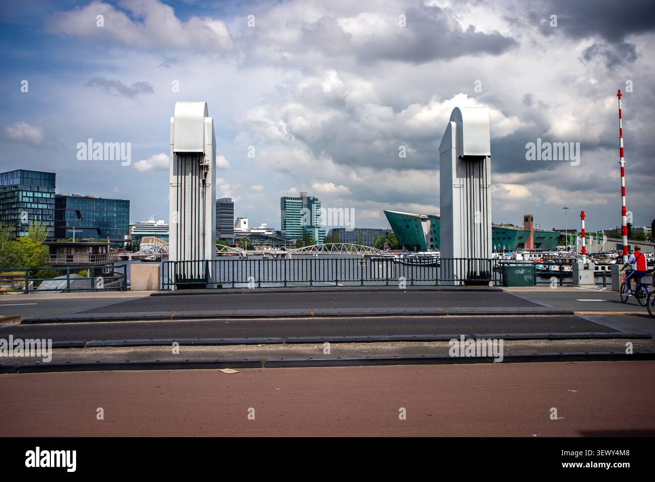 3. August 2024, Amsterdam, Niederlande: Eine Zugbrücke umrahmt die Uferpromenade von Oosterdok mit dem NEMO Science Museum und der Skyline der Stadt unter dramatischen Wolken. Stockfoto