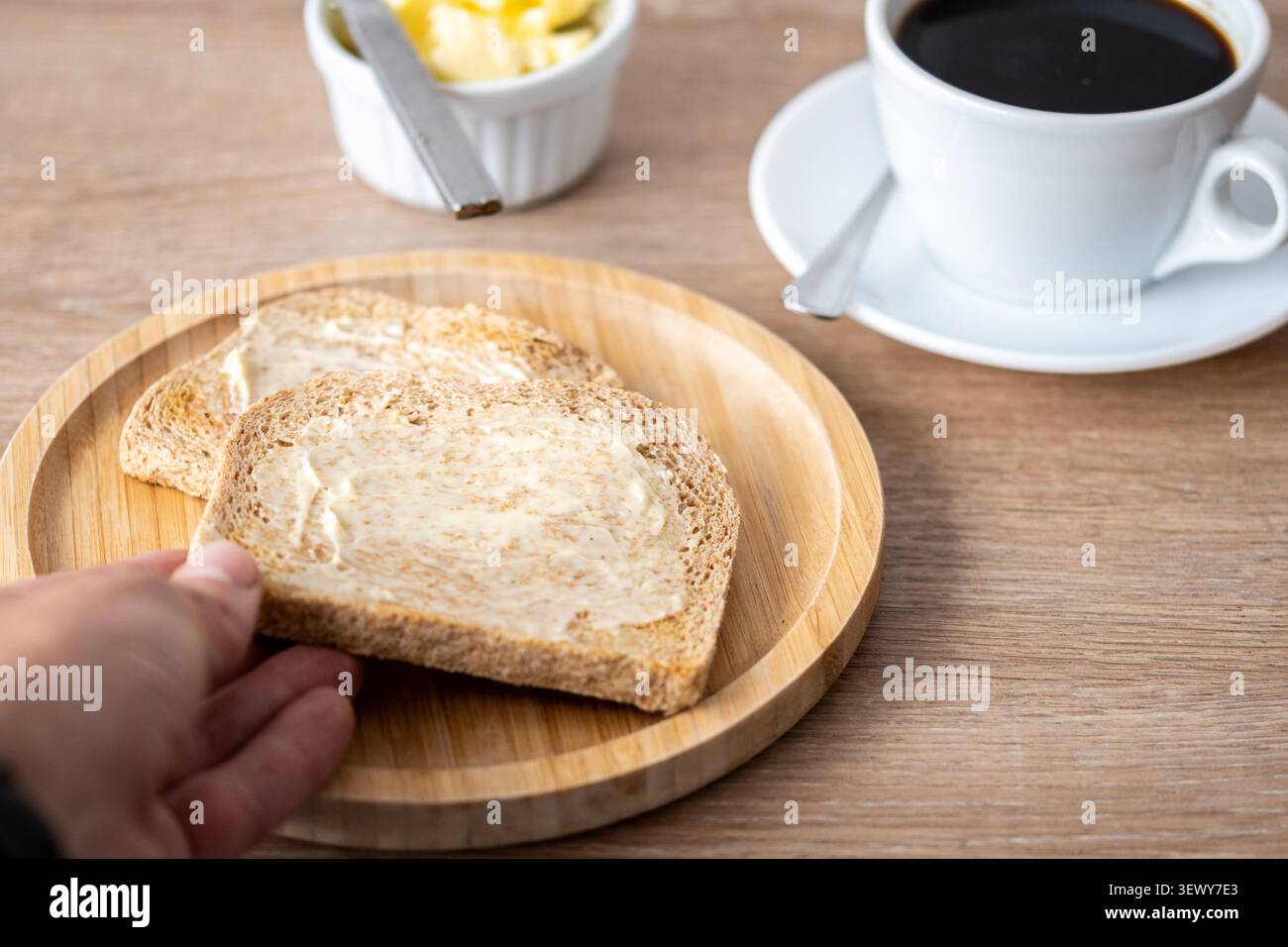 Gebutterter Vollkorntoast mit schwarzem Kaffee auf Holztisch Stockfoto