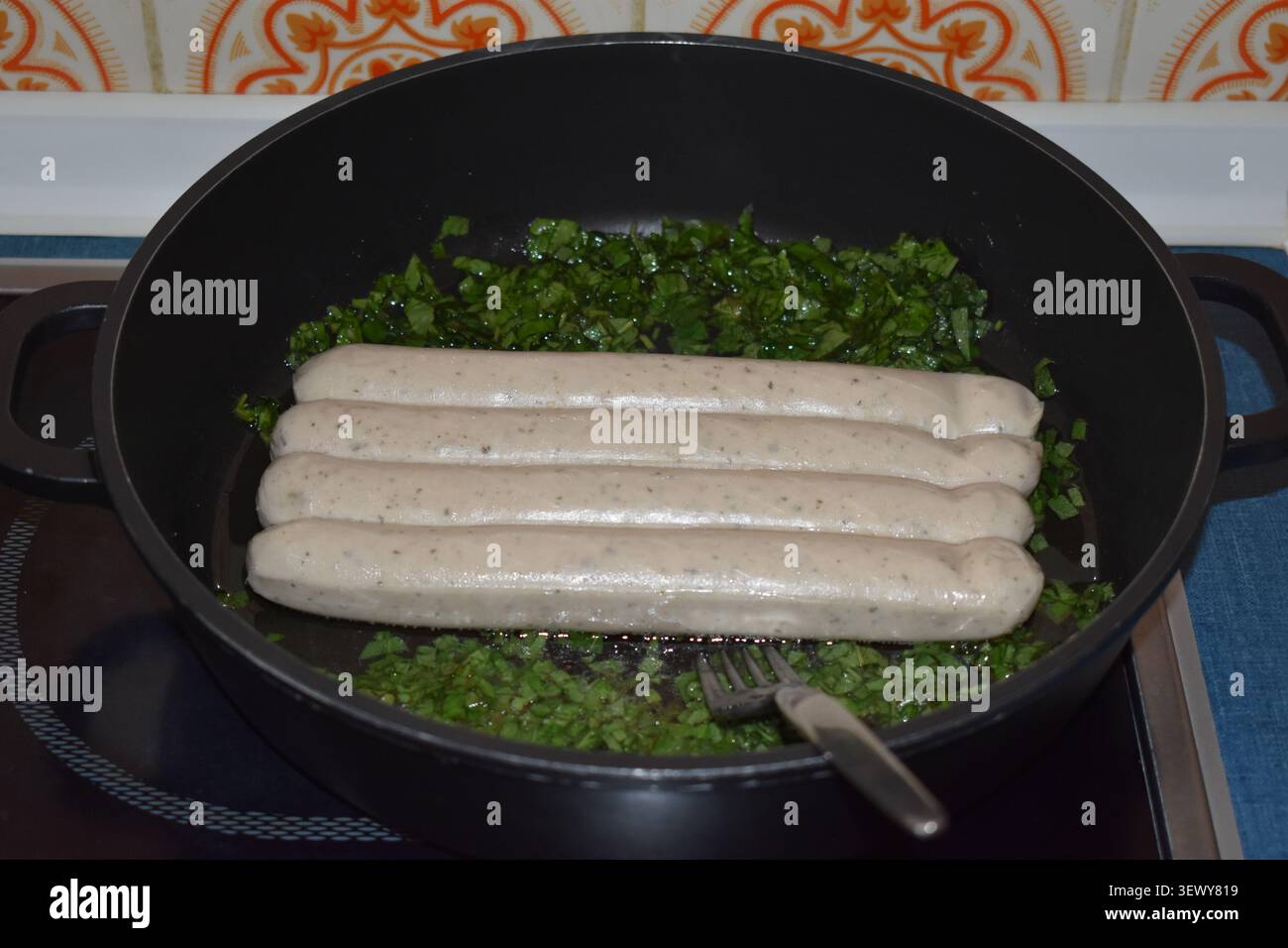 Bratwürste mit Kräutern in der Pfanne Stockfoto