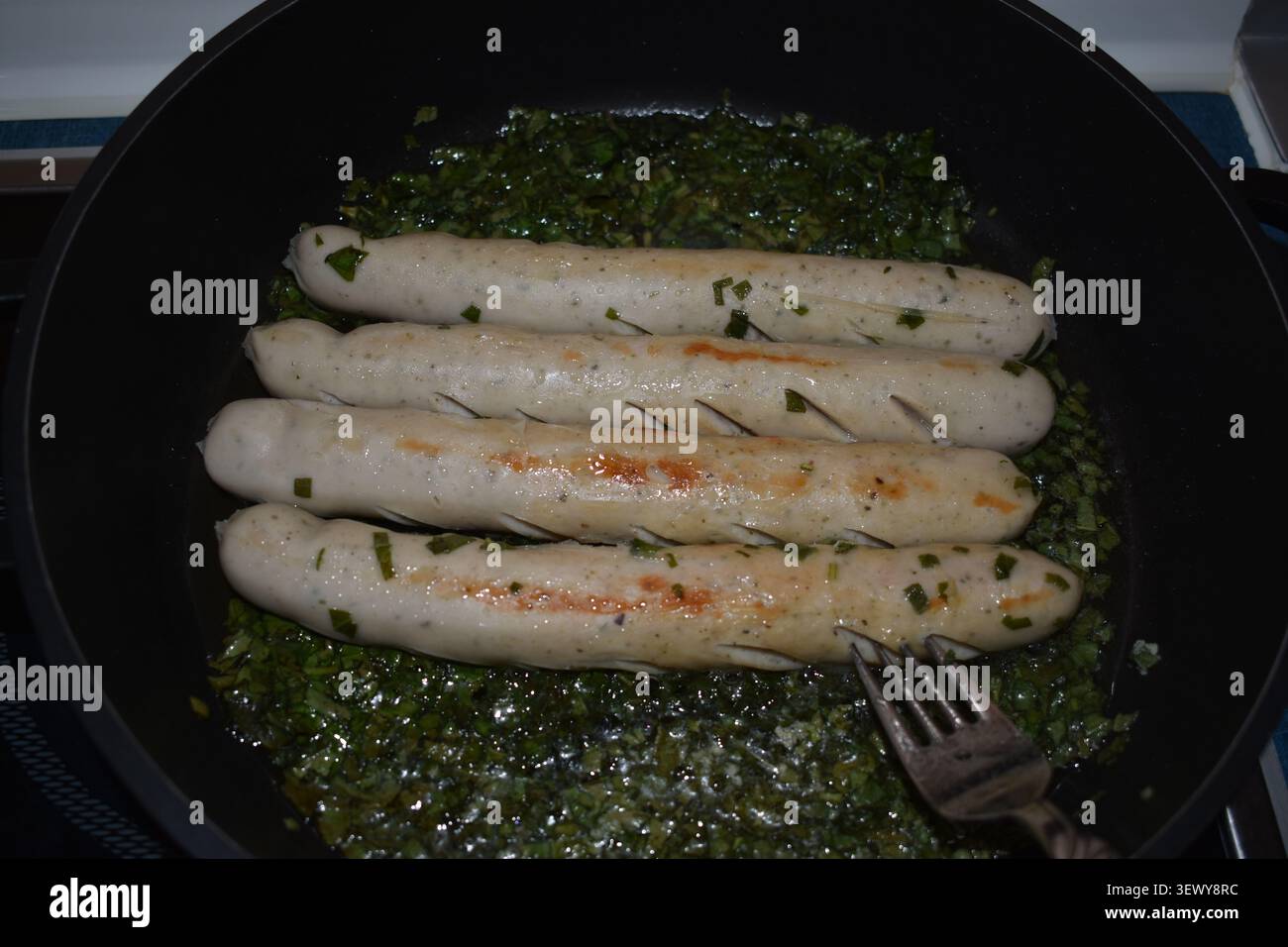 Bratwürste mit Kräutern in der Pfanne Stockfoto