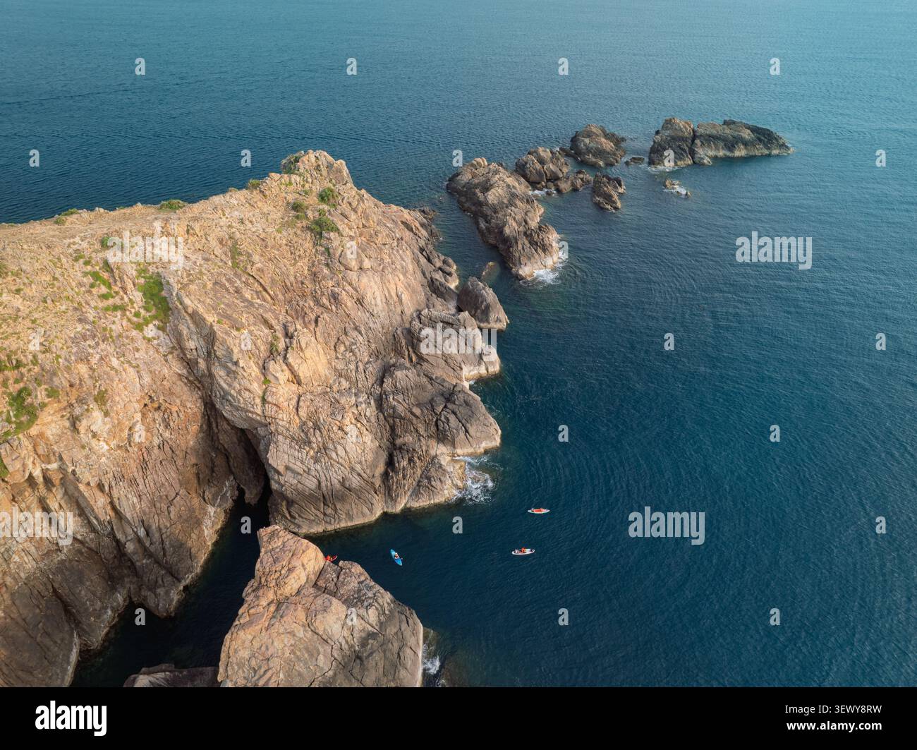 Blick aus der Vogelperspektive auf felsige Klippen und das ruhige blaue Meer am EO Gio, Quy Nhon, Gia Lai, vietnamesische Küste. Stockfoto